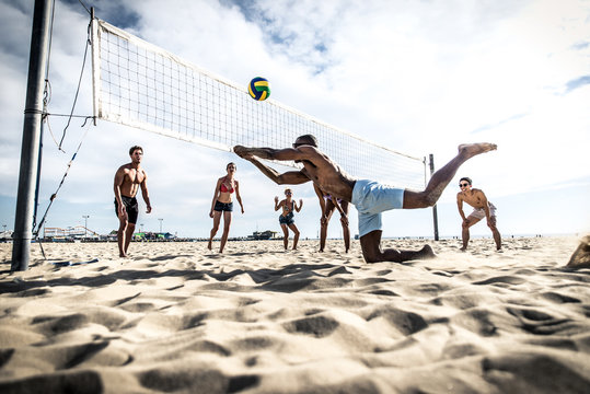 Group of friends playing beach volley on the beach.