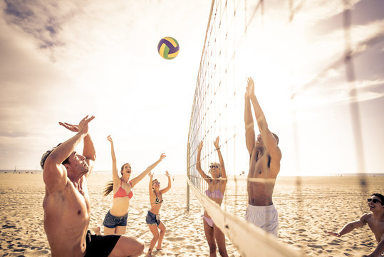 Group of friends playing beach volley on the beach.