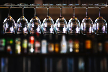 Group of wine glasses hanging above a bar rack in pub & restaurant - Powered by Adobe