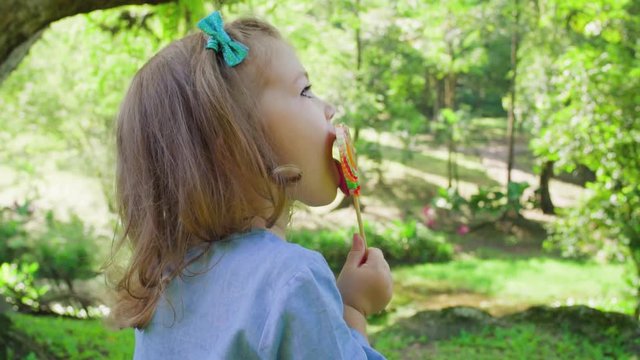 The girl licks the Lollipop in a beautiful Park