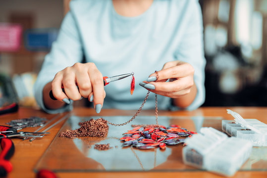 Female person holds pliers, bijouterie making