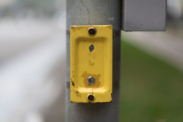Close up of yellow crosswalk button for pedestrian crossing at the street