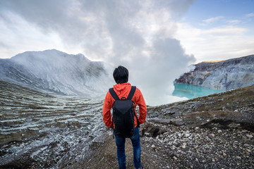 Young travler looking crater blue lake at Kawah Ijen, Indonesia