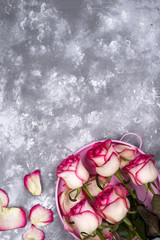 Red white rose flower bouquet with pink gift box on stone table.