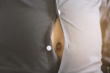 a person's torso with a shirt that is buttoned but stretched tight across their belly.