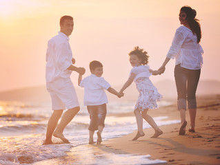 happy young family have fun on beach at sunset