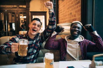 Cheerful male friends having fun at the beer pub celebrating victory of their favorite team...