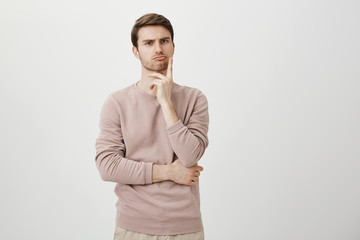 Portrait of unhappy determined european male with bristle touching chin while thinking and looking...