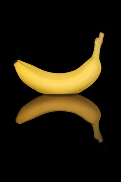 Image of a banana with black background and mirror image