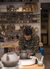 Fototapeta na wymiar Male artist makes clay pottery on a spin wheel