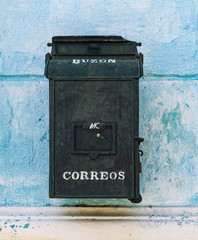 An old blue mailbox on a historic 16th century building.