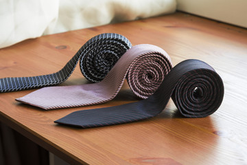 three men's tie rolled into a roll on a wooden background