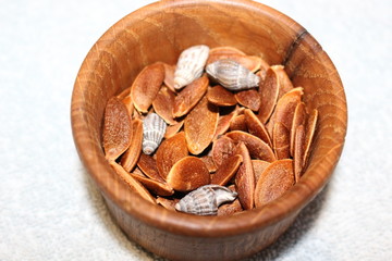 Seeds of persimmons and shells lie in a wooden box.