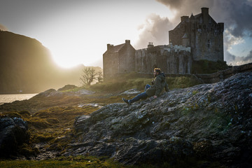 Sentado en una roca con vistas al castillo de Eilean Donan en Escocia