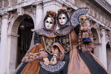 Obraz premium Two women in ornate costumes and painted masks, standing in St Marks Square during Venice Carnival (Carnivale di Venezia)