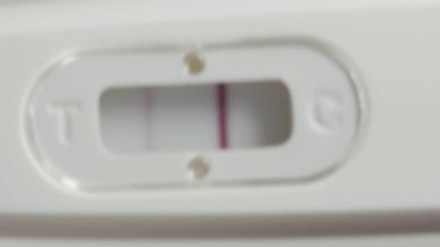 Positive pregnancy test in hands. Extremely close up shot.