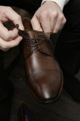 Ein brauner Herrenschuh wird angezogen