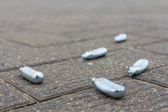 empty nitrous oxide bulbs lying scattered on the street, also known as laughing gas or hippie crack recreational drug, lying scattered on the street
