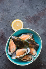 Black bowl with raw kiwi mussels, close-up, selective focus, horizontal shot