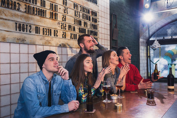 Group of young beautiful friends watching TV and cheering for th