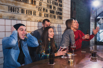 Group of young beautiful friends watching TV and cheering for th