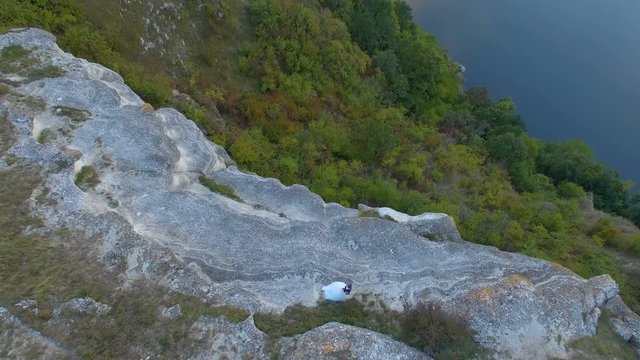 Great sunset on the lake between the mountains. A couple hugging at the edge of the cliff. 4k