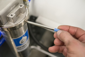 Worker tighten industrial water filter by hand