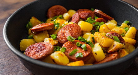 Roasted Potato and Sausage in frying pan on wooden table