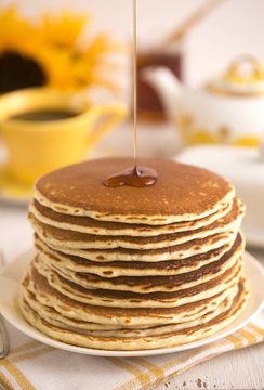 A Stack Of Fresh Buttermilk Pancakes With Syrup Being Poured Out