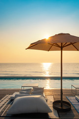 Beautiful luxury swimming pool on sea view and umbrella and chair in hotel resort with sunrise - obrazy, fototapety, plakaty