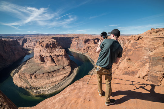 Tourist man taking photo on camera and tripod during his travel in Grand Canyon, USA
