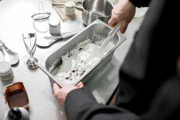 Chef mixing ice cream with chocolate in the metal tray on the kitchen