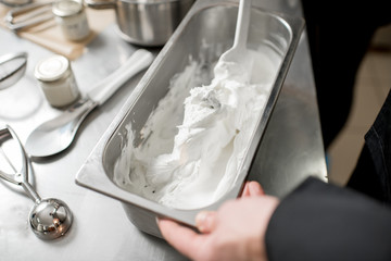 Chef mixing ice cream with chocolate in the metal tray on the kitchen