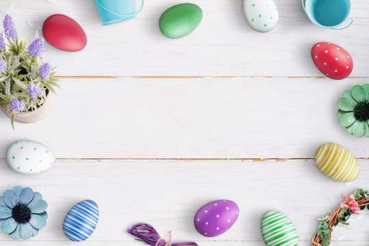 Easter composition with colorful eggs on white wooden background. Free space in the middle for text.
