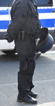 Polizist mit Uniform und Helm vor einem Einsatzfahrzeug 