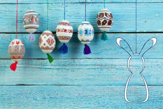 Happy Easter card. Colorful shiny easter eggs and rabbit on blue wooden table background. Copy space for text.