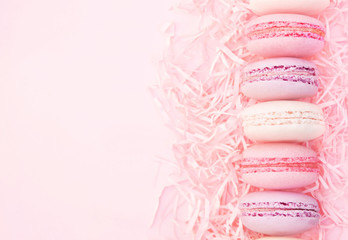 Raspberry and strawberry pink macarons on pastel valentine decor and rose flowers soft background, selective focus, toned