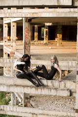 Two sexy girls are posing on the columns of the abandoned building