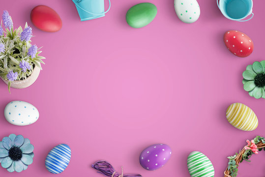 Top view of Happy Easter composition with flat lay colorful eggs and decorations. Pink background.