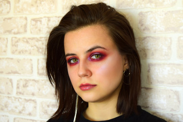 Portrait of the young beautiful girl with green eyes and a bright creative make-up in lilac tones....