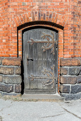 Old wooden door, rusty hinges and lock, brick wall