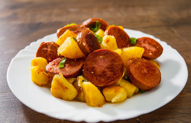 Roasted Potato and Sausage in white plate on wooden table