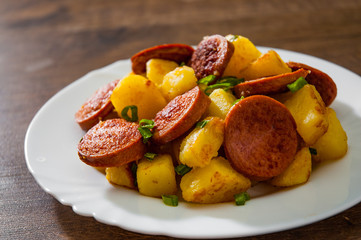 Roasted Potato and Sausage in white plate on wooden table