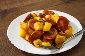 Roasted Potato and Sausage in white plate on wooden table