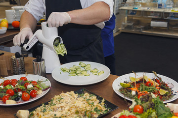 Cook in the kitchen cuts vegetables for salad