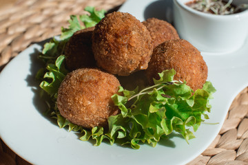 closeup of plate with spanish croquettes served with salad and sauce