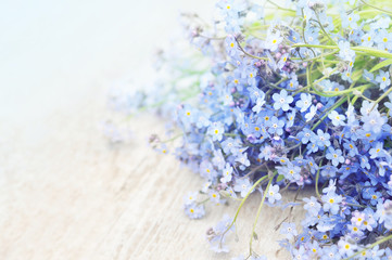 Spring blue forget-me-nots flowers posy on wooden background , pastel background, selective focus, toned floral card