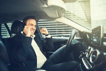 Businessman sitting in his car celebrating success with fist pum