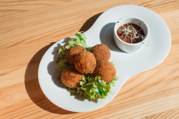 closeup of plate with spanish croquettes served with salad and sauce