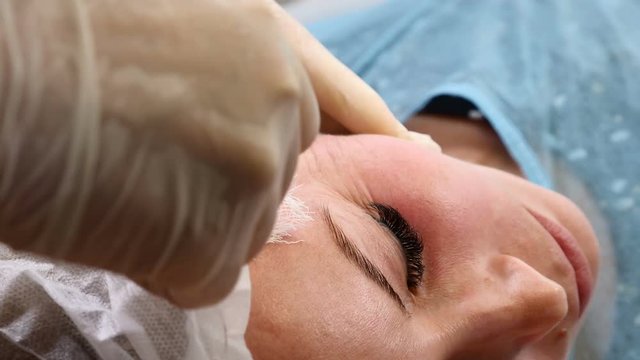 Beauty clinic. Young female client gets thread face lifting. Cosmetologist in gloves making face anti-aging to a female face